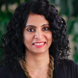 Deepa Poduval with black blouse smiles at camera.