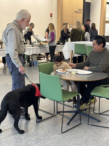 A dog and their handler at Wags N Waffles visiting with a parent and child.