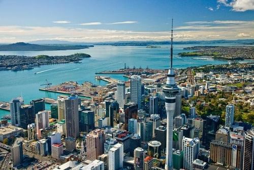 Aerial view of Auckland, New Zealand, with the Sky Tower, overlooking the harbor and surrounding landscape.