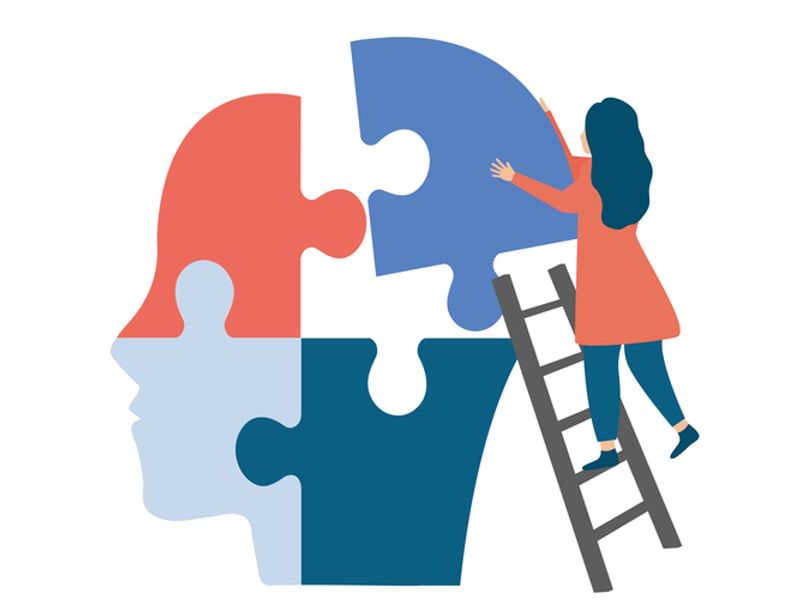 A woman assembling puzzle pieces to create a head, showcasing focus and creativity in her task.