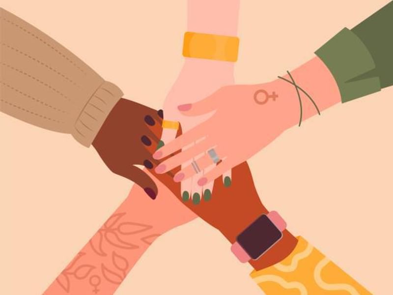 Five diverse hands stacked together in unity.
