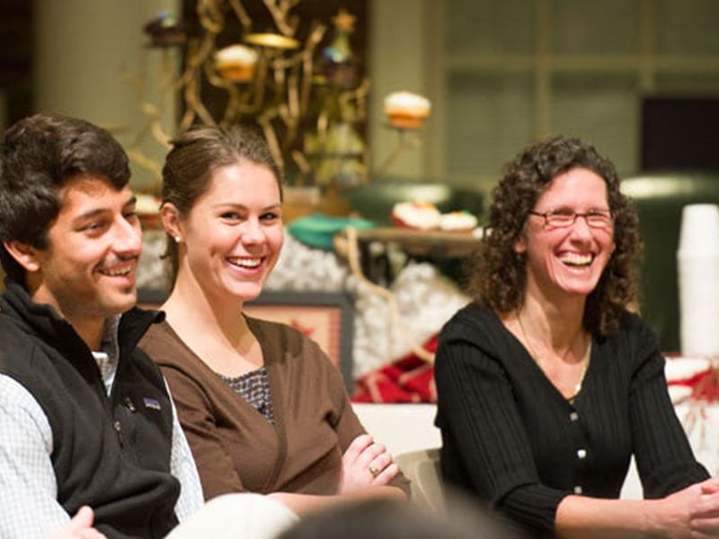 Three people smiling at a ceremony.